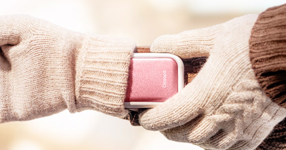 person slipping a pink hand warmer into their glove