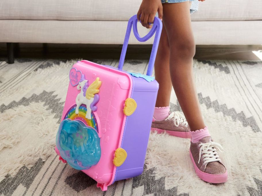 Little girl rolling a Polly Pocket Pollyville Suitcase Set