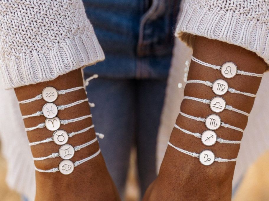 Woman with wrists filled with Pura Vida Zodiac Charm Bracelets