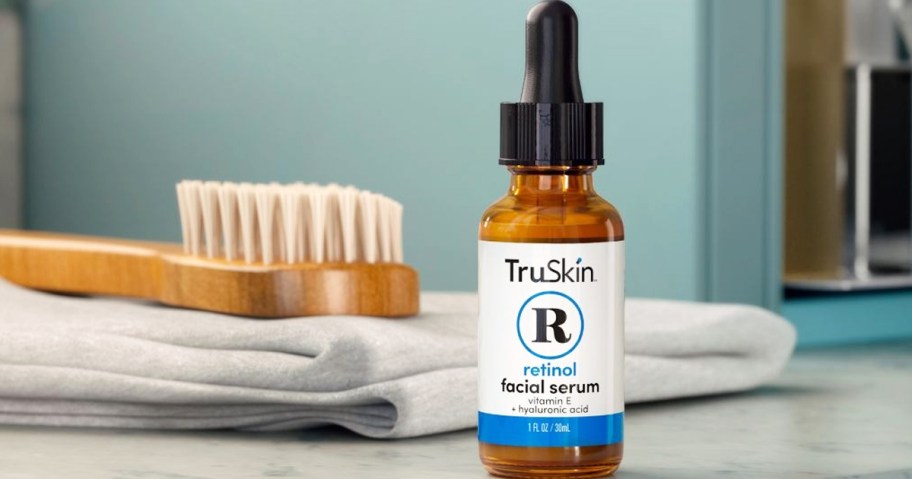 bottle of TruSkin Retinol Serum on bathroom counter near towel and body brush