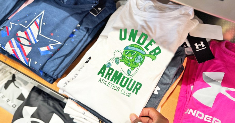 hand grabbing under armour graphic tee fromt store shelf
