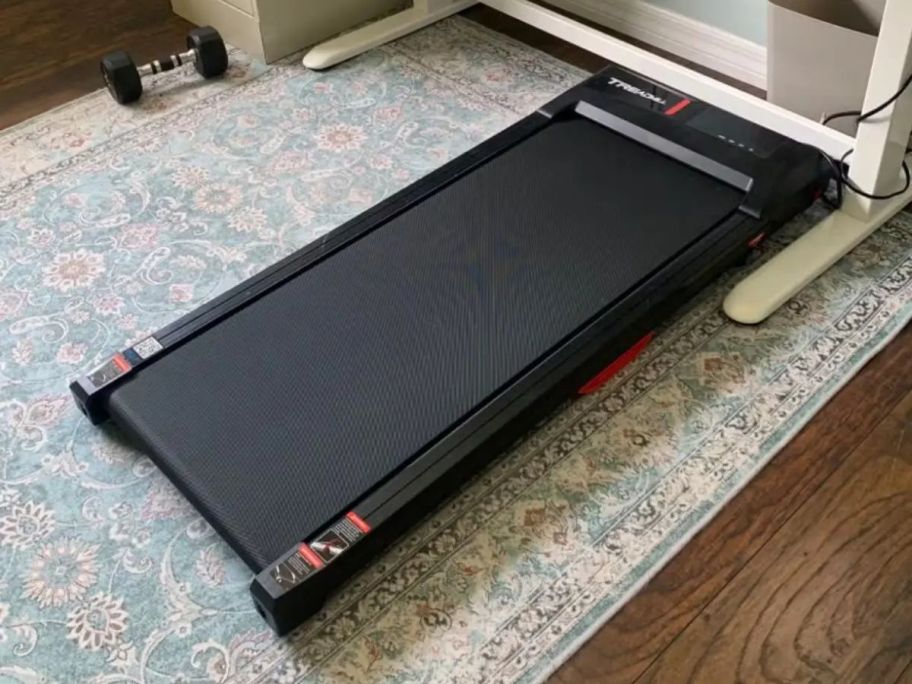 A walking pad underneath a desk 