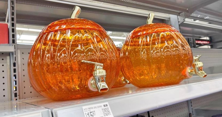two orange glittery acrylic pumpkin beverage dispensers on store shelf