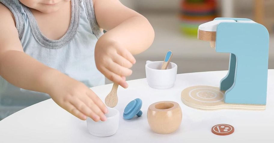 A child playing with a wooden coffee maker