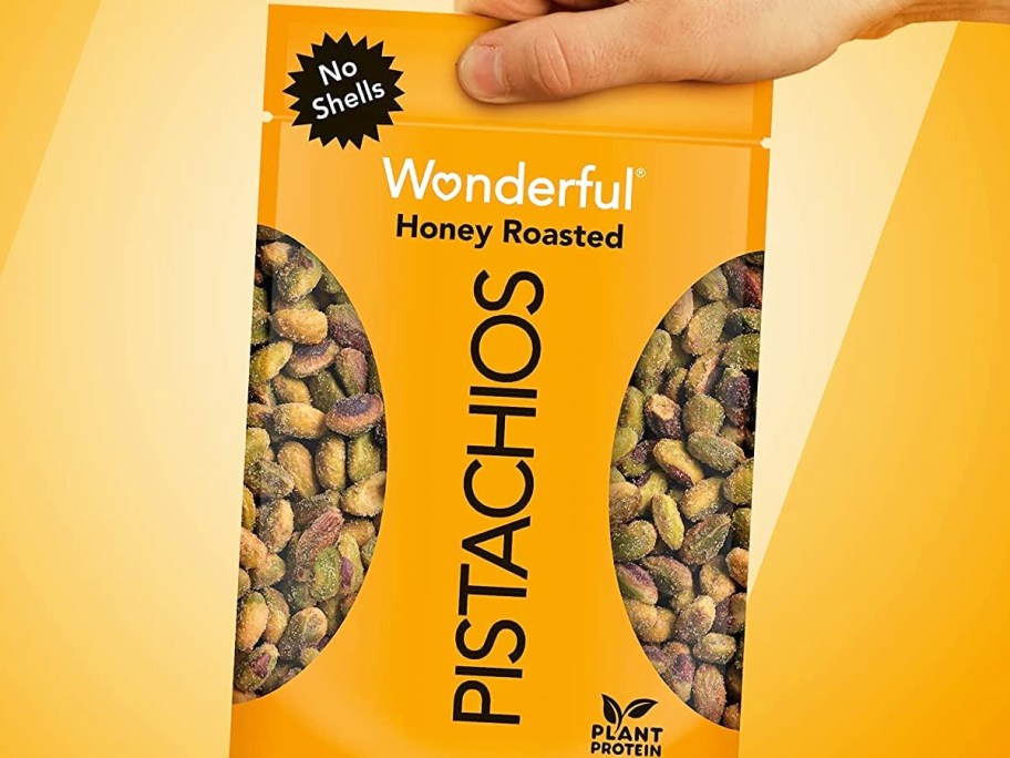 holding up a yellow bag of Wonderful Pistachios in Honey Roasted flavor