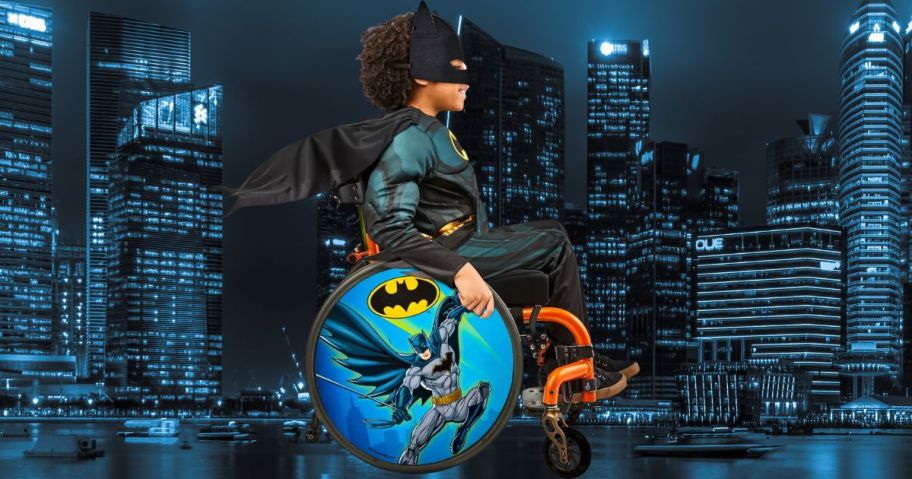 kid in wheelchair wearing batman costume in front of city scene