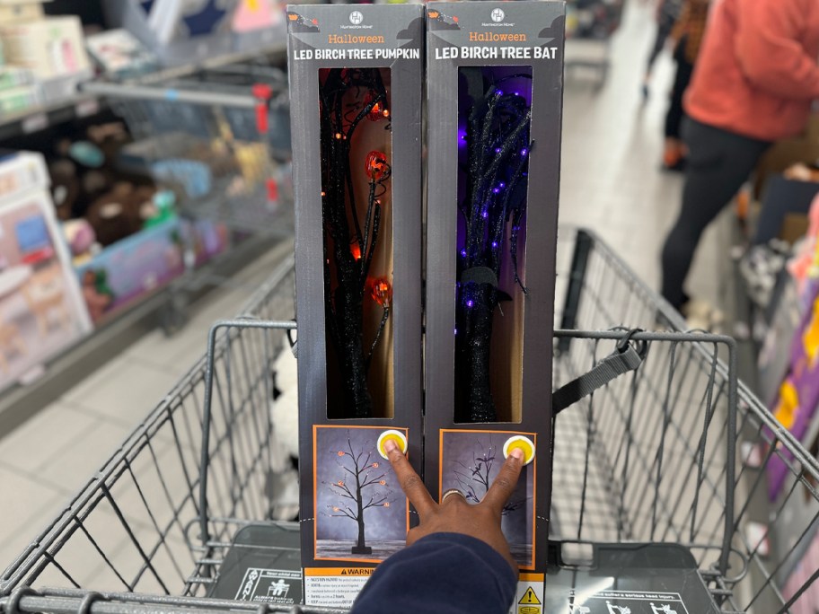 hand pushing light button on two birch trees in shopping cart 