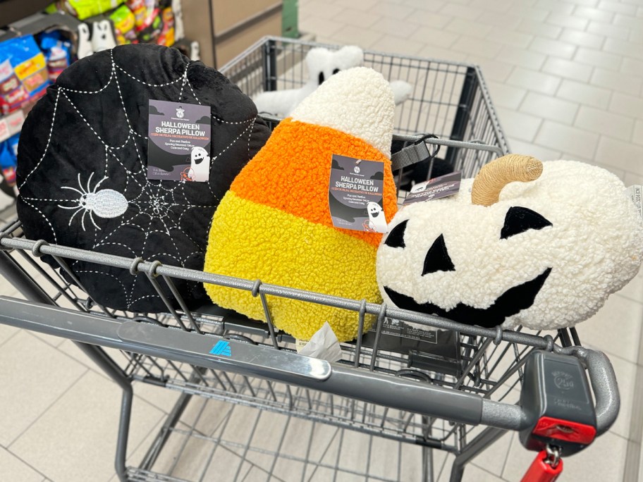 spiderweb, candy corn, and pumpkin sherpa pillows in aldis cart