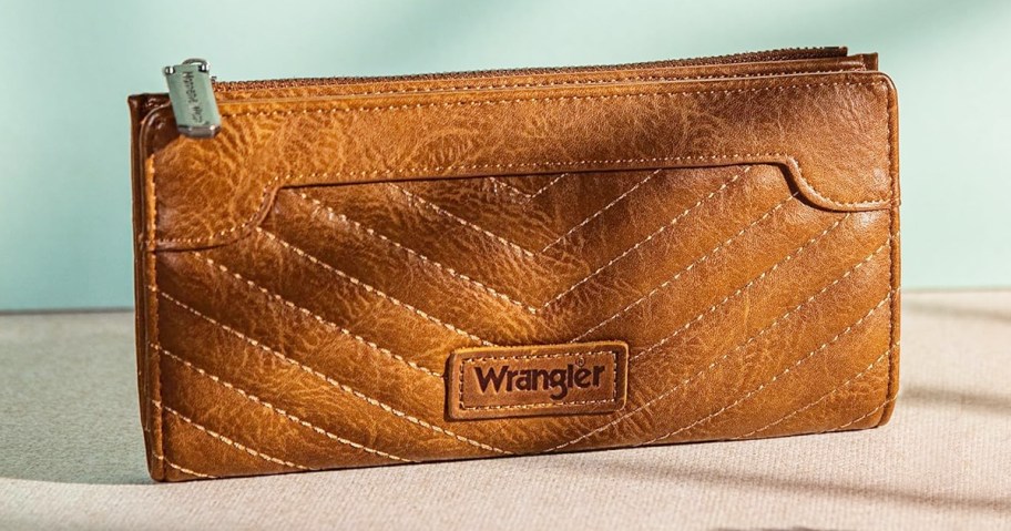 brown wrangler wallet sitting near teal wall