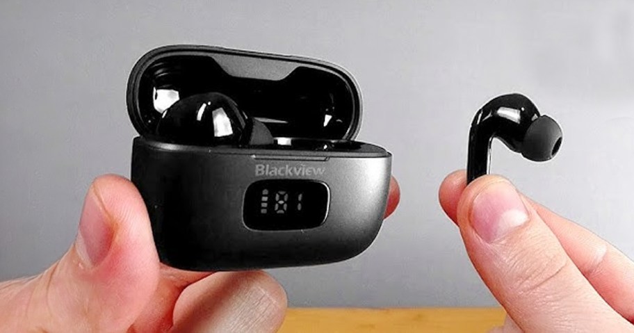 hand holding black earbuds and case 