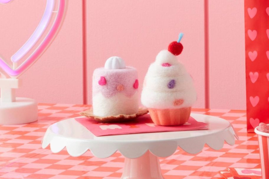 two felt cupcake figurines on a cake stand