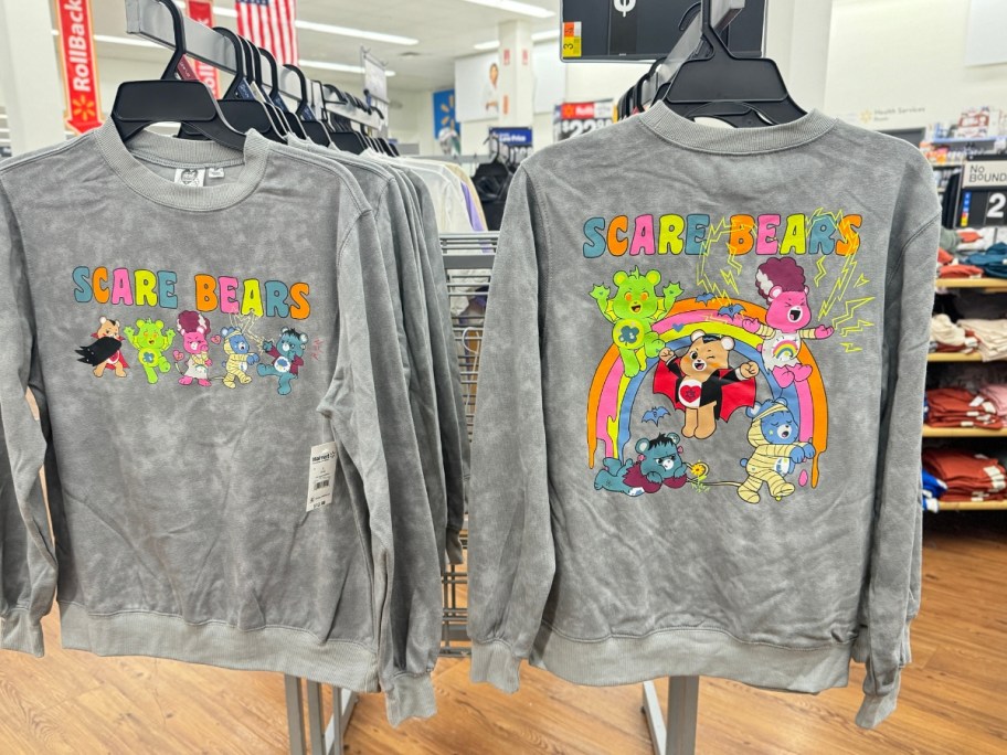 grey wash sweatshirts on a rack in store showing the front and back of a Care Bears "Scare Bears" Halloween sweatshirt with Care Bears dressed as Halloween characters and the words "Scare Bears"