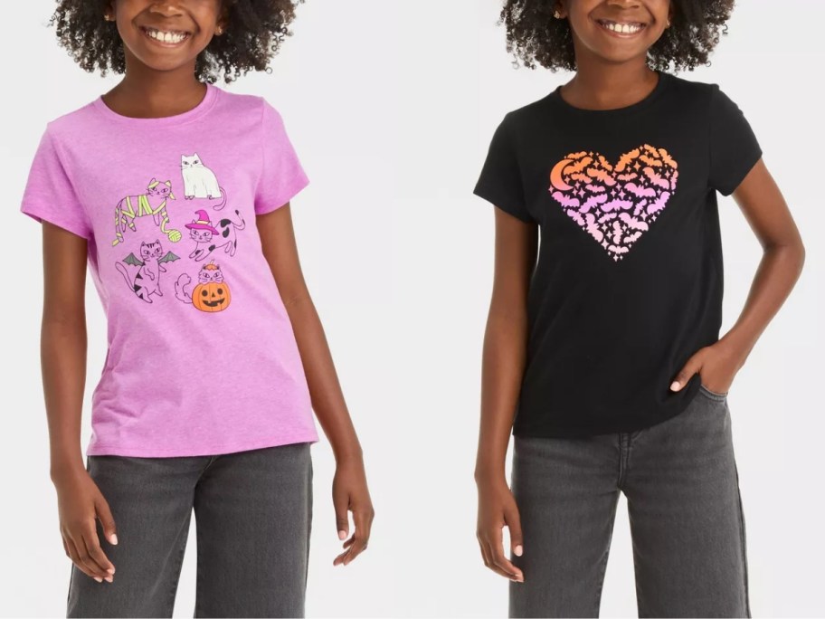 girl wearing a pink tshirt with Halloween graphics on it and girl wearing a black t-shirt with a heart and bats on it