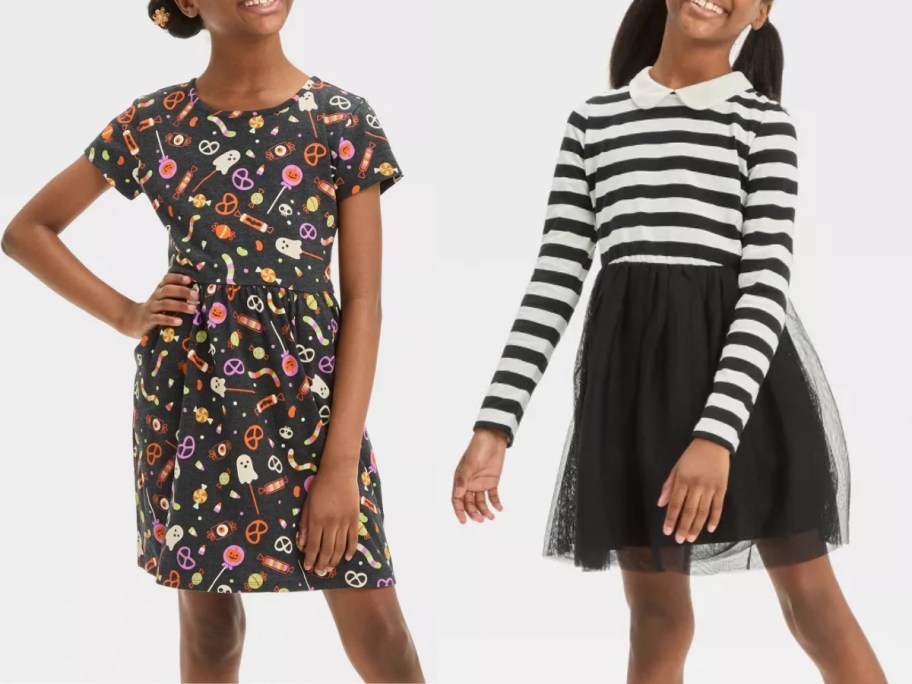 girl wearing a black dress with a Halloween print on it and girl wearing a dress with a black and white stripe top and black tulle skirt