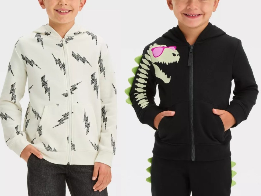 boy wearing a black and white lightning bolt zip up Halloween hoodie and boy wearing a glow in the dark Halloween dinosaur hoodie