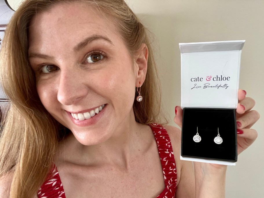 woman wearing halo drop earrings and holding them in box