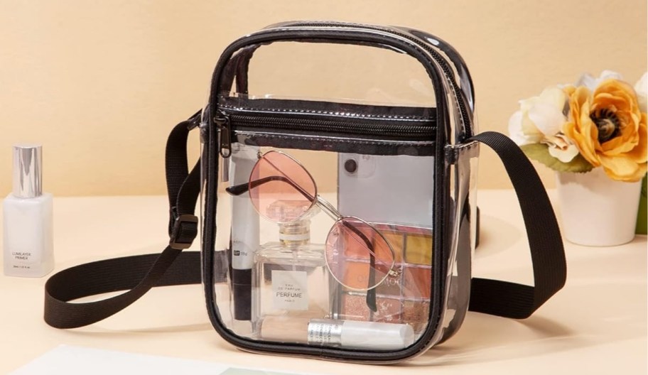 clear crossbody bag with sunglasses and other items inside