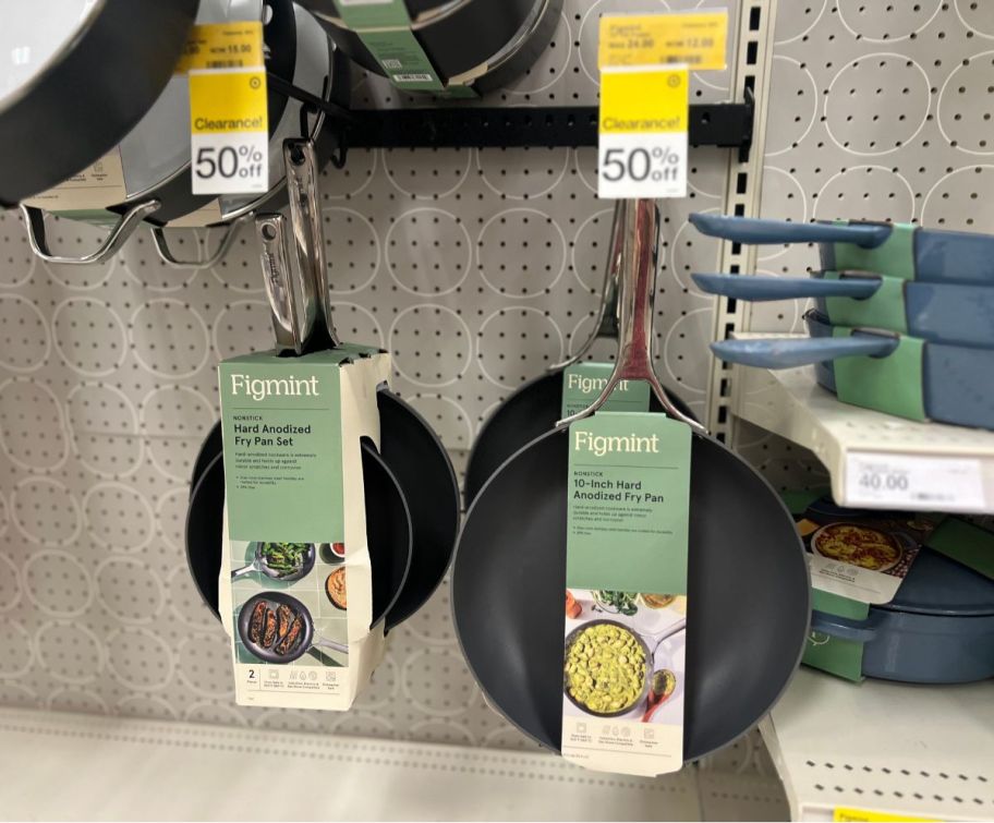 figmint frying pans on a pegboard on a store aisle.