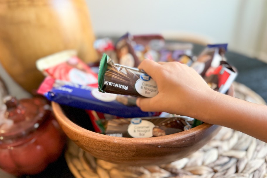 hand grabbing candy bar out of bowl