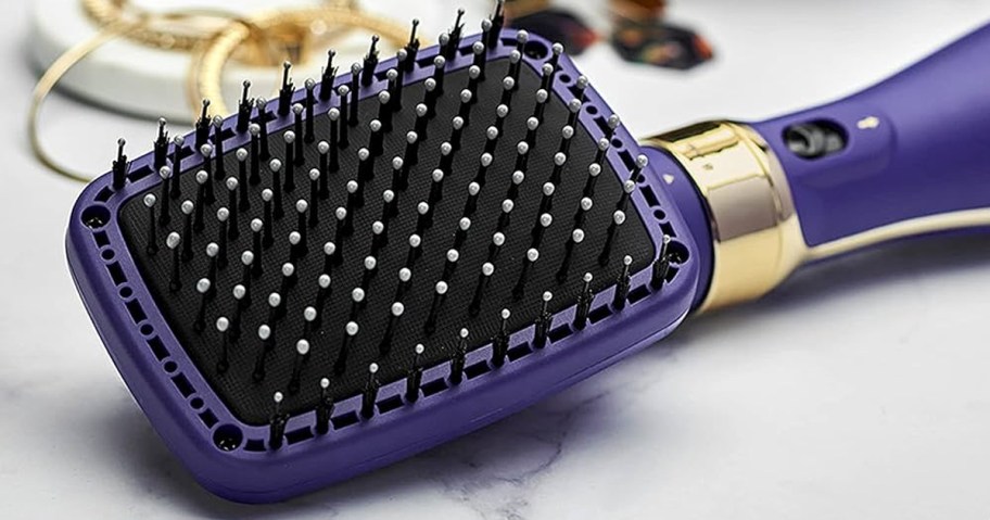 purple and black paddle hair straightener on table