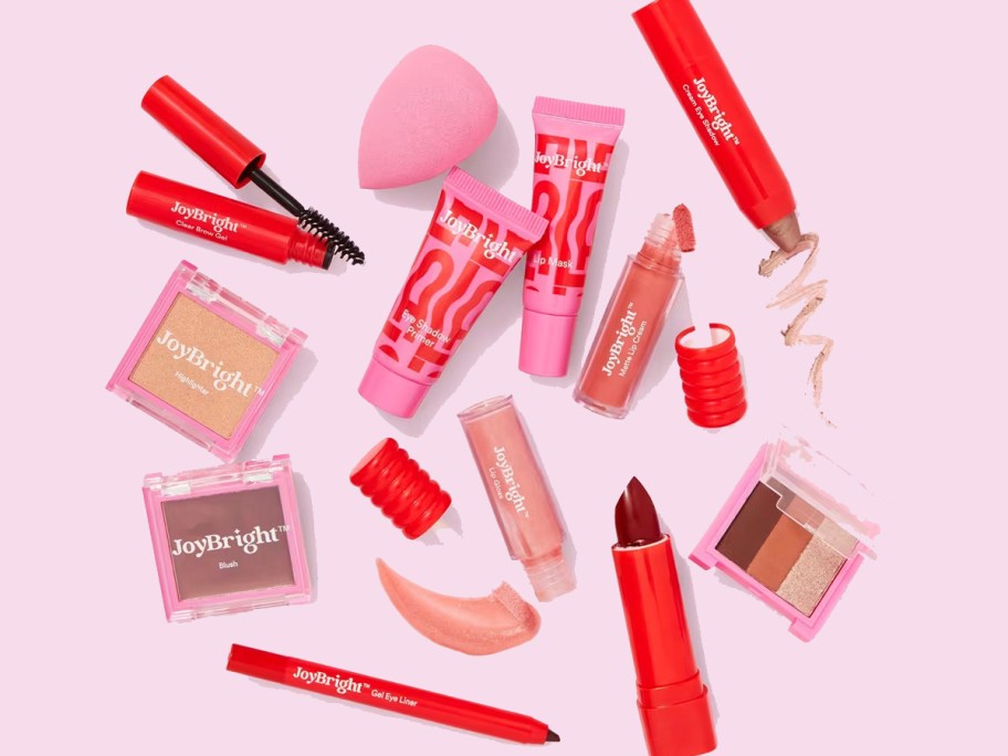 lots of joybright makeup products in red laying on pink table