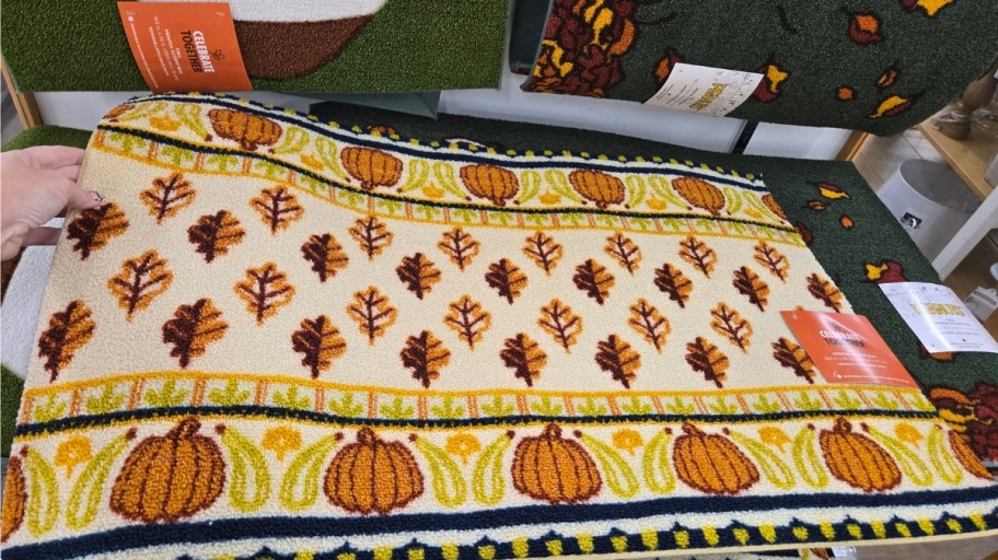 a doormat with a leaf and pumpkin pattern