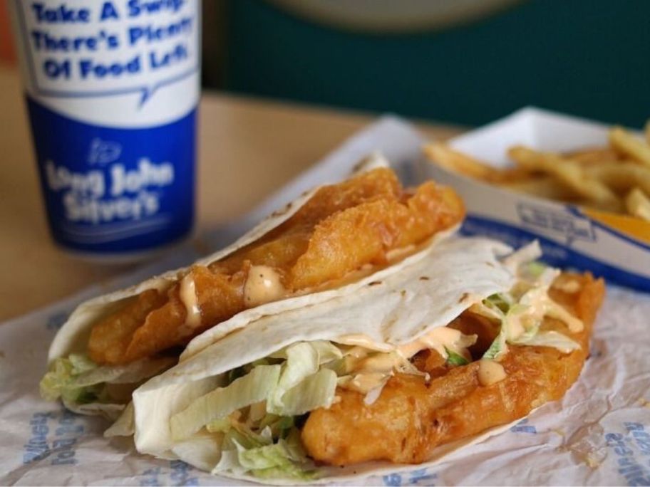 two long john silver's tacos on table with drink and fries