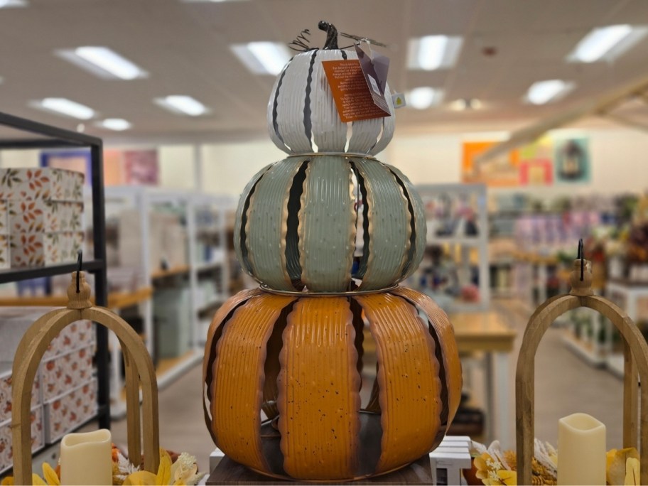 a metal pumpkin stack with a weathered finish on a display table in a store