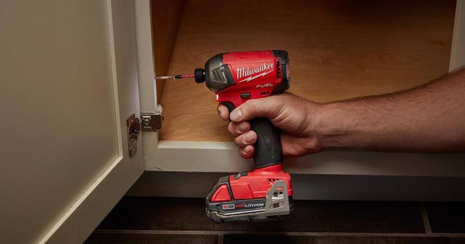 person using Milwaukee power tool on door