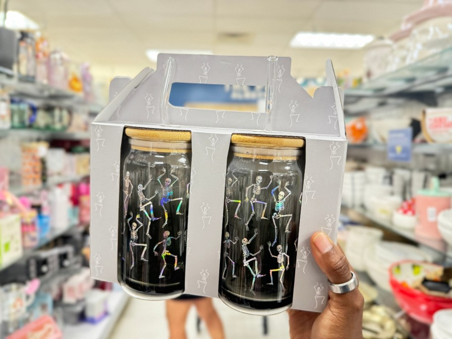 hand holding a box with 2 glass tumblers with bamboo lids that have dancing skeletons on them