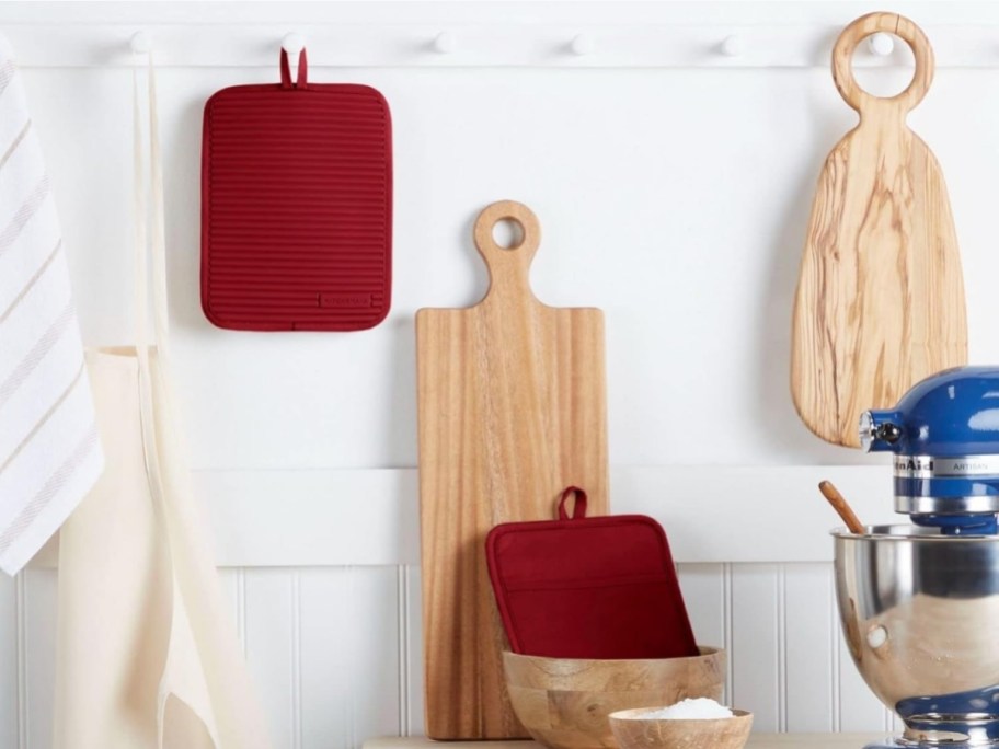 two red rectangular oven mitts displayed in a kitchen scene
