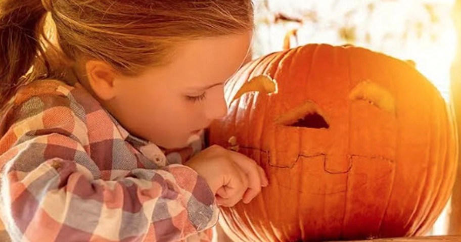 girl carving face into pumpkin