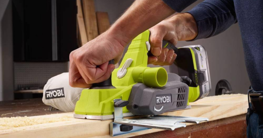 person using RYOBI power tool on wood board