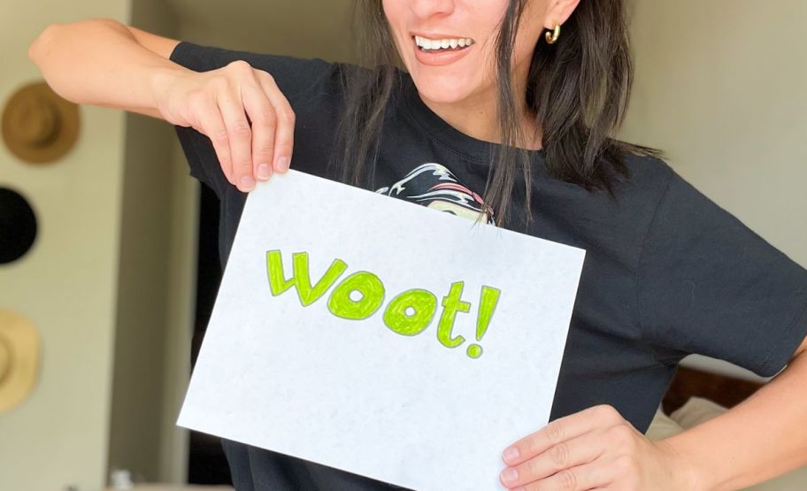 a woman holding a sign that reads WOOT! in lime green letters