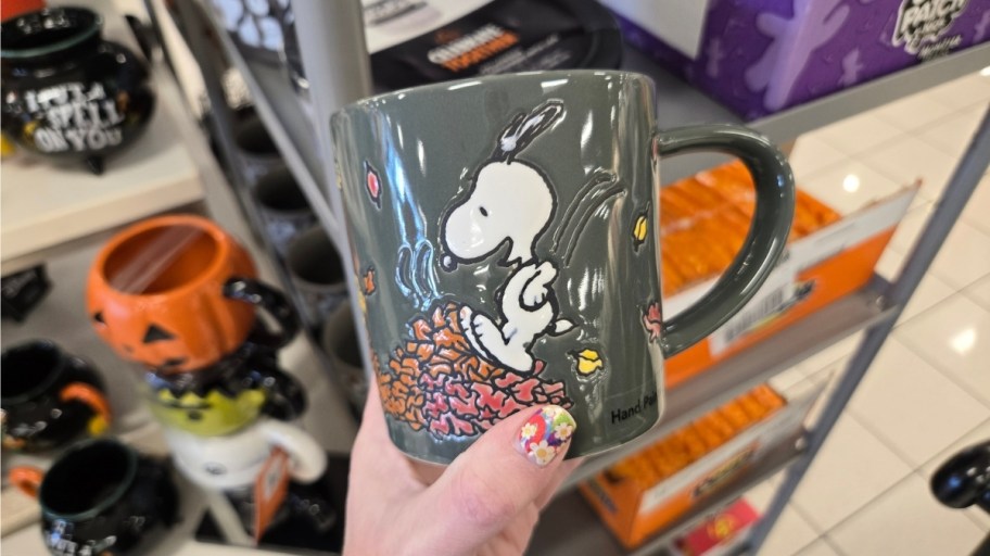 a coffee mug with snoopy and woodstock jumping in piles of leaves