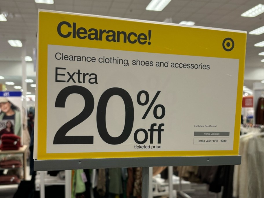 a yellow and white sign that says "Clearance Extra 20% off ticketed items" on a clothing rack in Target