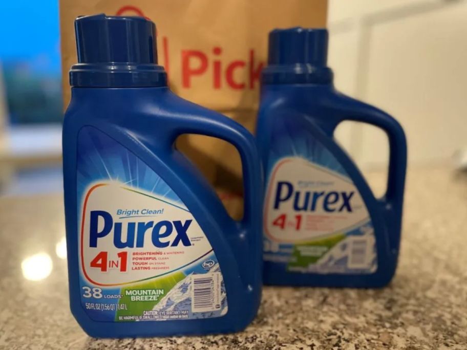 Two bottles of Purex laundry detergent by a Walgreens bag