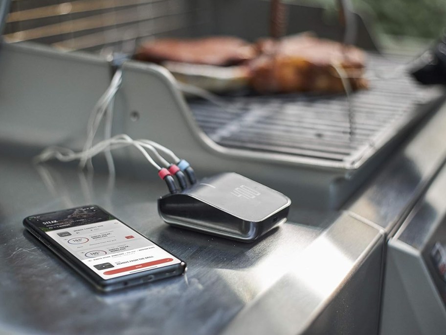 phone and electric thermometer next to grill