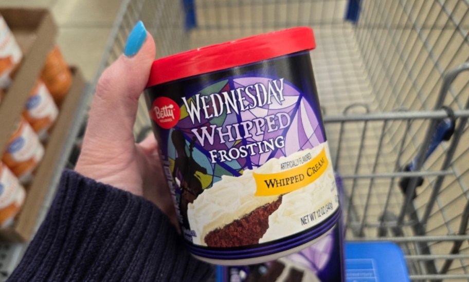 a womans hand holding a jar of cake frosting