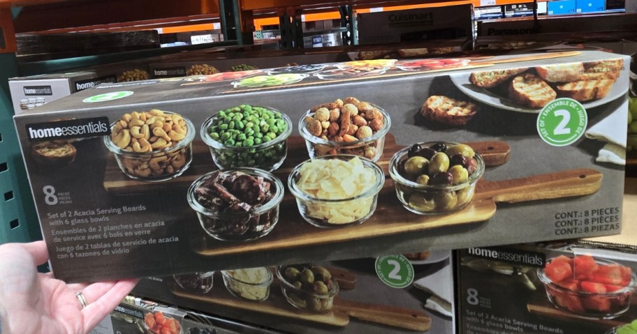 hand holding a box with a wooden serving board with 3 glass bowls, boxes of them behind it on a Costco shelf