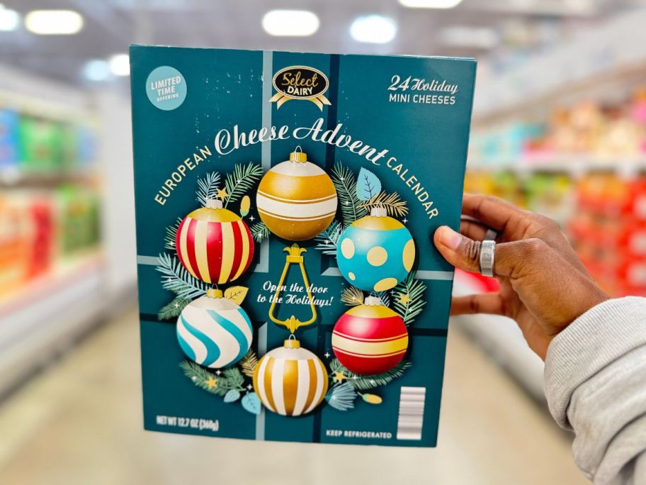 a womans hand holding a holiday mini cheese advent calendar