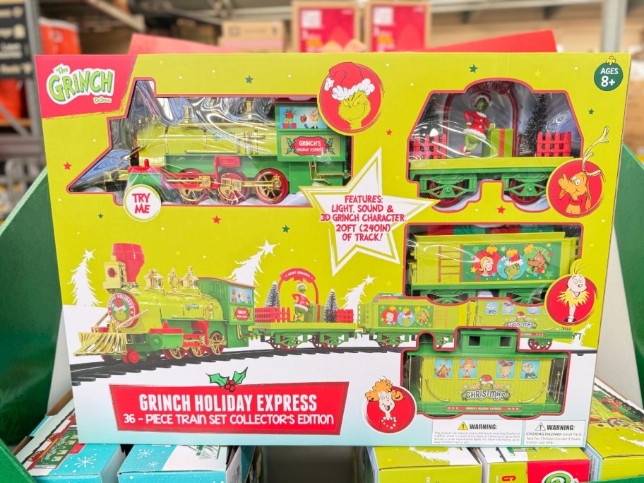 large green box with a 36-Piece Battery Operated Grinch Holiday Express Train on a store display