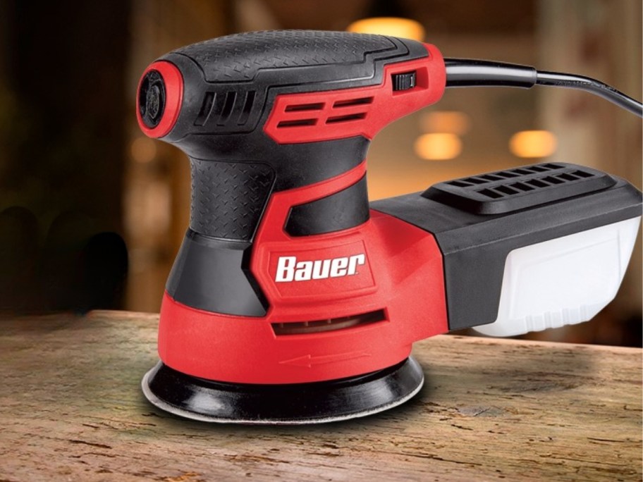 red and black BAUER round Palm Sander on a piece of wood