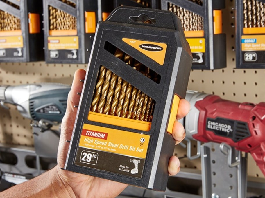 hand holding a Warrior Titanium 29-Piece Drill Bit Set with more on a wall behind it
