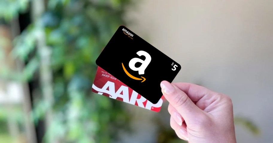 Hand holding amazon gift card and AARP membership card