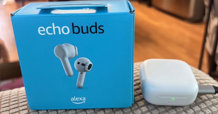 A pair of white earbuds with a box on a table