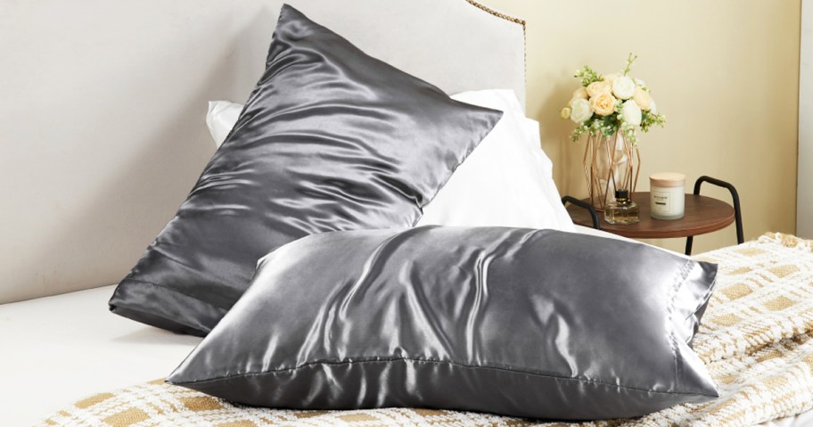 two pillows in grey satin pillowcases on bed