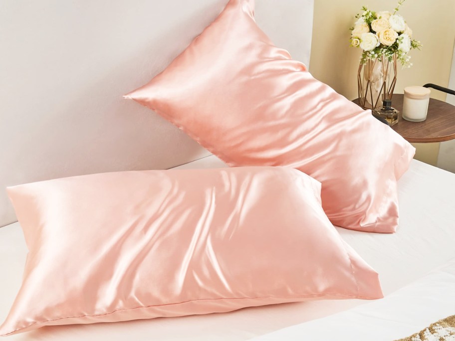 two pillows in light pink satin pillowcases on bed