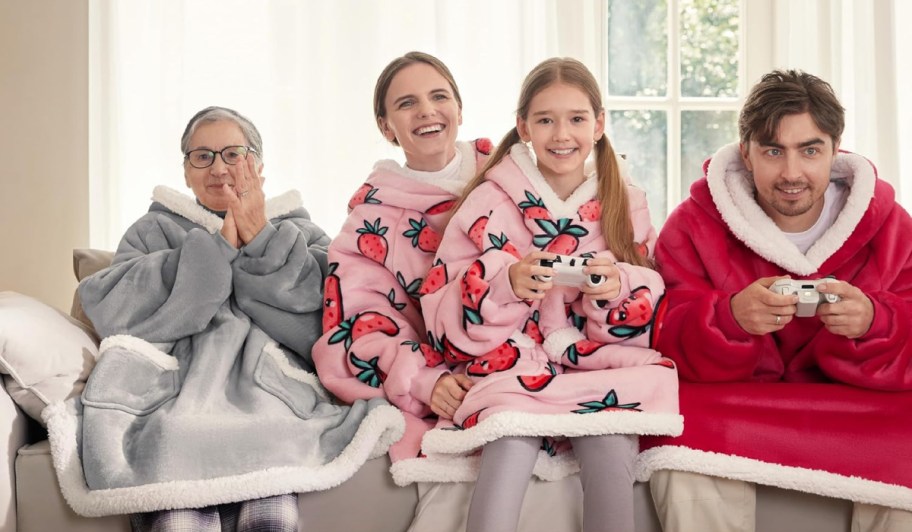 Four people on a couch wearing wearable blankets.