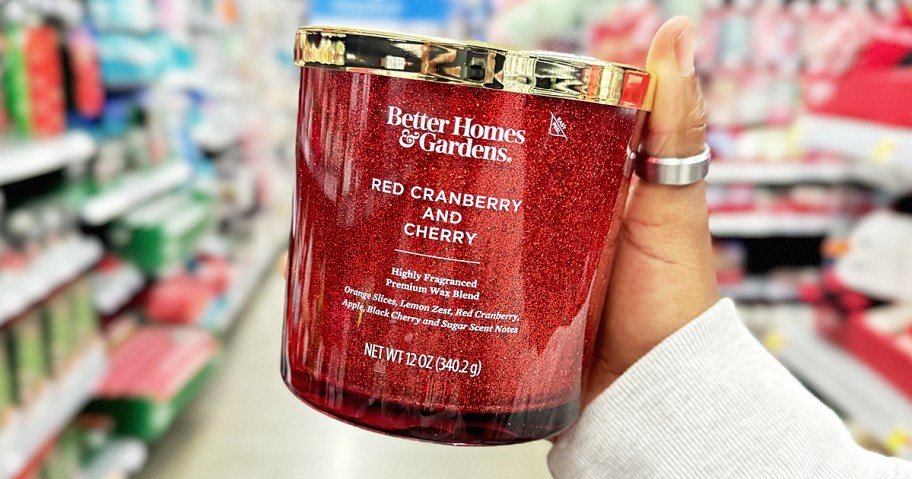 hand holding up a red glittery jar candle in store